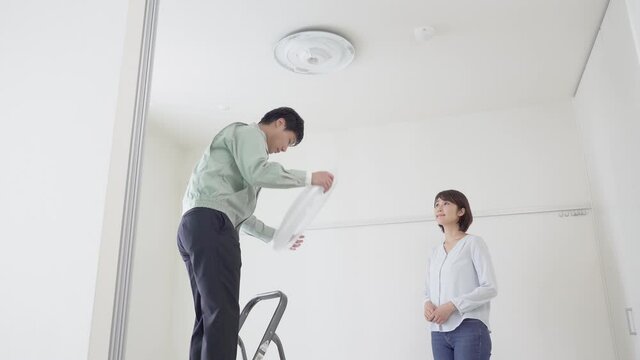 天井にシーリングライトを取り付ける作業員