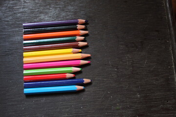 Many colored pencils on a black background. New pencils. Isolated background to insert text, selective focus