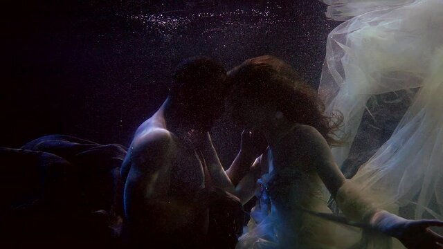multiracial loving pair underwater, swimming and embracing, love and passion