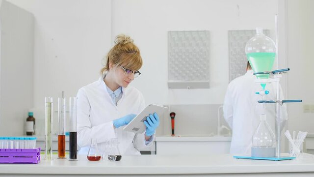 Chemist working with hemp CBD oil and tablet in laboratory