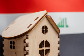 Small wooden house, Iraq flag on background. Real estate concept, soft focus