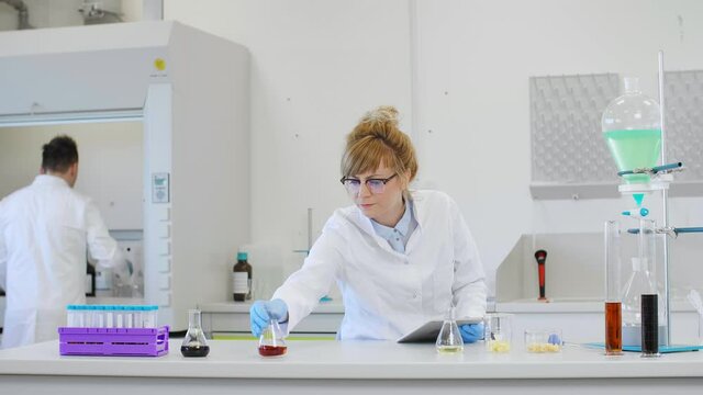 Chemist working with hemp CBD oil and tablet in laboratory