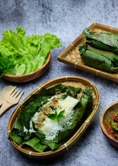 Indonesian traditional Javanese nasi bakar (grilled rice) menu complete with side dishes squid and anchovies served with sambal (like spicy sauces) and lalapan (fresh vegetables)