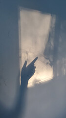 Shadows of hand pointed gesture with forefinger touching into window