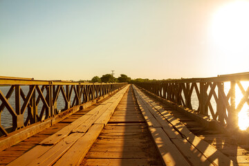 Old floating wooden bridge with green iron railings that crosses part of the Ibera Wetlands