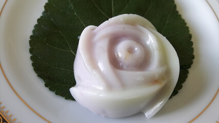Sweet rose-shaped jelly dessert placed on a leaf in a white tile dish.
