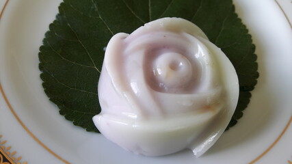 Sweet rose-shaped jelly dessert placed on a leaf in a white tile dish.