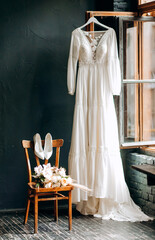 Fototapeta na wymiar Wedding interior. The brides dress hangs near the window. Vintage style. Bridal morning details.