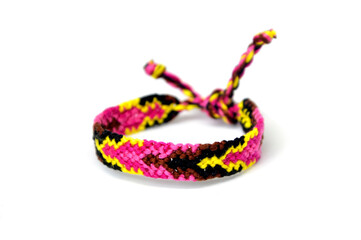 Selective focus of tied woven friendship bracelet with bright colorful pattern handmade of thread isolated on white background