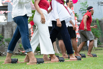 two groups of participants tried to run during the traditional bakiak race on Indonesia's Independence Day celebration in the field with balloons and small red and white decorations