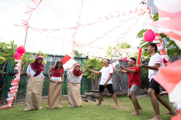 male supporters wearing the red and white attribute shouted in support of the women's sack racer event commemorating Indonesia's Independence Day celebrations on the lawn