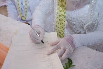 The hand of a bride signs the file after the marriage consent is granted.