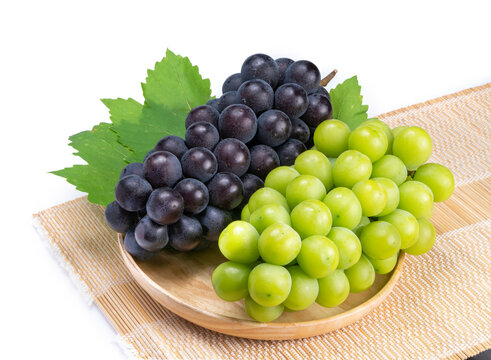 Sweet Green grape and Black grape in Bamboo basket isolated on white background, Shine Muscat Grape and Kyoho Grape with leaves isolated on white 
