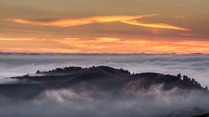 Sunset above the clouds. Fog covering the Pacific Ocean as seen from Russian Ridge Open Space Preserve, San Mateo County, California, USA.