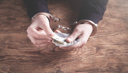 Hands in handcuffs counting dollar banknotes. Corruption