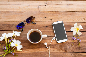 mobile phone ,hot coffee ,sunglasses and white flowers frangipani of lifestyle woman relax arrangement flat lay style on background wooden 