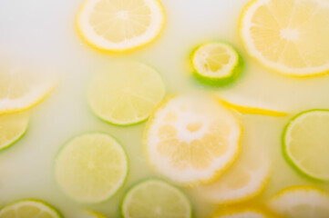 Turbid soapy water in the bath with slices of lemon and lime top view in full frame. Citrus. Spa with milk in the bath for rejuvenation.
