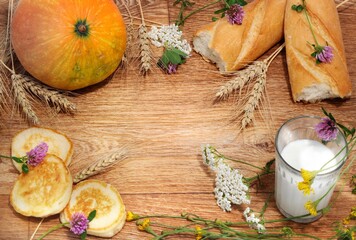 autumn still life in the form of a frame made of homemade village products Pumpkin milk bread Wheat ears pancakes flowers on wooden background