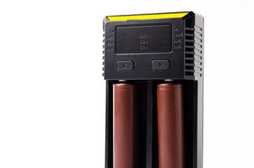 A black charger for two 18650 batteries. A green and brown 18650 battery on a white background next...