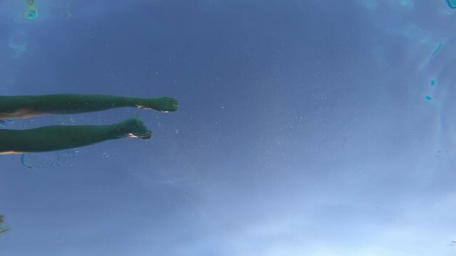 underwater shot of young relaxed woman swimming in the pool