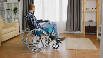 Invalid young guy and depressed in wheelchair .