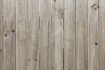 Wooden background in natural gray. Old rustic fence with cracks and rusty nails.