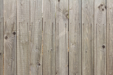 Wooden background in natural gray. Old rustic fence with cracks and rusty nails.