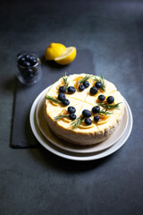 Homemade cheesecake with fresh blueberry and candied lemon on black stone background.