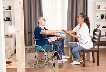 Fototapeta premium Disabled old man during physiotherapy talking with doctor about his pain. Disabled handicapped old person with social worker in recovery support therapy physiotherapy healthcare system nursing