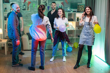 Beautiful young woman smiling while having a conversation on her phone at a party.