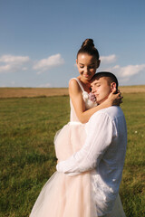 Newlyweds walking in field. Groom hug bride after wedding ceremony