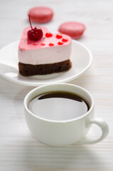 souffle cake in the form of heart  with cup of coffe and macaroons on a wooden table