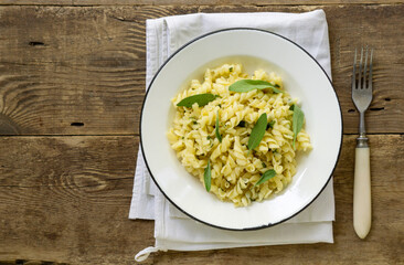 Fusilli pasta with sage leaves in a white bowl