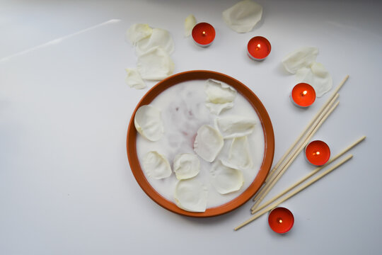 Beautiful spa composition of white rose petals and candles on white background.