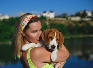 portrait of a young woman with a beagle puppy in her arms