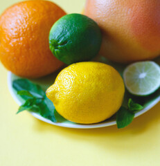 ripe juicy citrus fruits on a green plate on a yellow background