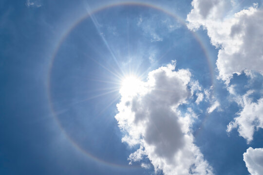 Sun halo phenomenon, circular rainbow around the sun on blue sky.