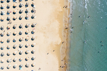 Fototapeta na wymiar Aerial view of a shallow sandy beach and sunshade with sun umbrellas. Tourism and holiday concept.