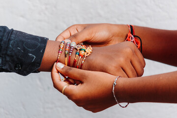 Closeup shot of hand of a sister binding rakhi on her brother`s hand on the occasion of Raksha Bandhan