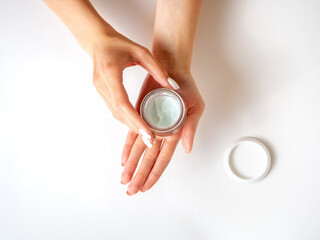 the girl's hands are holding a jar of cream. White background. Top view