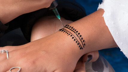 Artist applying henna tattoo on woman hand. Mehndi is traditional Indian decorative art