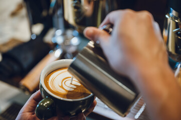 Fototapeta na wymiar barista making latte art, shot focus in cup of milk and coffee, vintage filter image