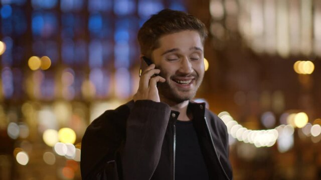 Cheerful man answering phone call on street. Handsome guy speaking mobile phone.