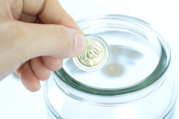 Close up women hands put coin in jar. Saving money growing business concept.