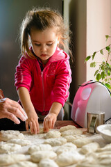 Fototapeta premium Grandmother and granddaughter sculpt dumplings with meat filling.