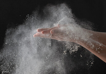 Obraz na płótnie Canvas wave of hands with flour on a black background