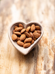 Peeled almonds in a wooden plate on a natural wooden background. Macro.