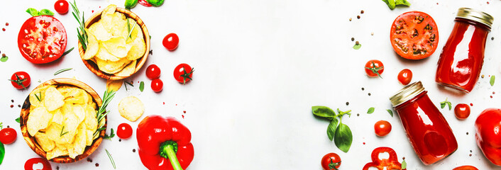 Potato chips with salt and rosemary with tomato juice, chili and pepper, spices and green basil, top view. Panoramic banner with copy space