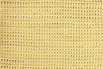 Real, yellow knitted fabric fragment made of wool fibres textured background, with delicate pattern.