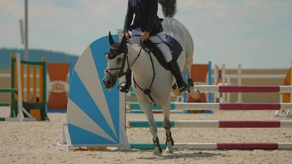 Horse jumping over obstacle on sandy parkour riding arena equestrian competition